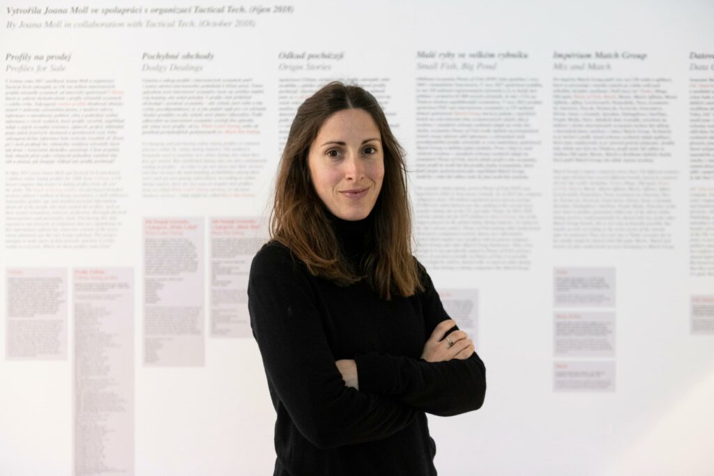 A portrait photo of artist and researcher Joana Moll standing in front of her work