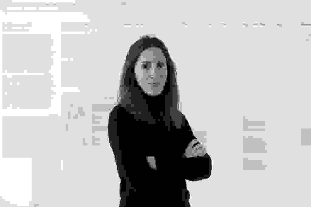 A portrait photo of artist and researcher Joana Moll standing in front of her work