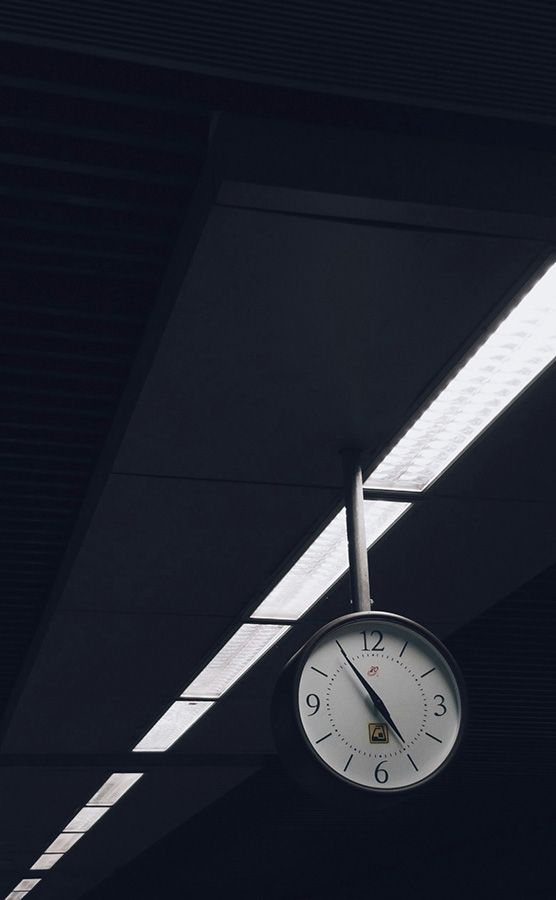 A dark ceiling with a large clock hanging from it and strip lights